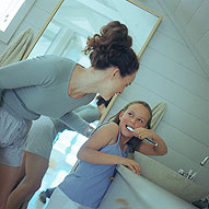 Daughter brushing teeth with her mother